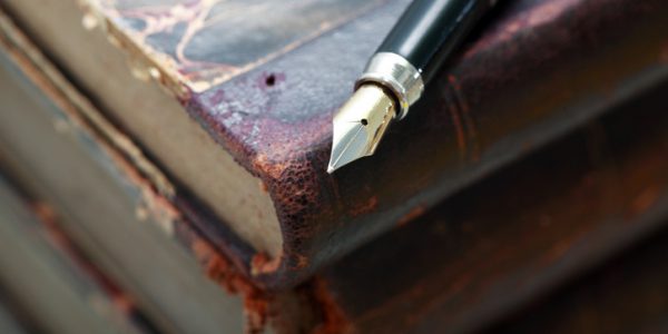 Closeup of fountain pen on stack of old books